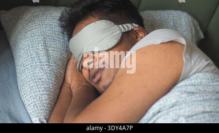 Man sleeping with eye mask in bed during the night Stock Photo