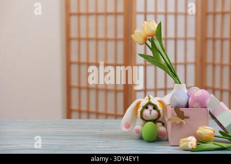 Easter Decor. Adorable bunny with tulips and colorful eggs in a serene setting. Stock Photo
