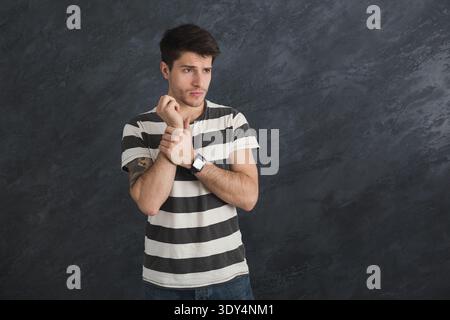 Pensive young man with smartwatch in studio Stock Photo