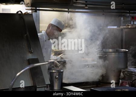 Chef cooks in steam in a kitchen galley Stock Photo