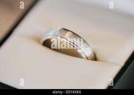 Close up of a mens silver wedding band resting inside a jewelry box. Symbol of marriage, commitment and groom wedding jewelry. Stock Photo