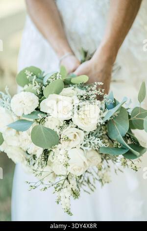 Bride holding white wedding bouquet with roses and greenery Stock Photo
