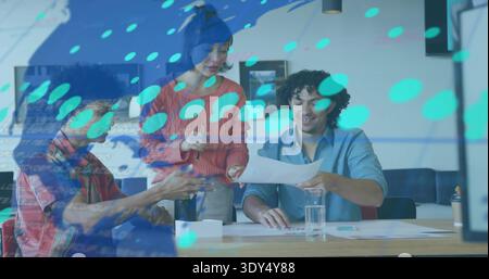 Three colleagues reviewing documents at table in office with teal overlay, wearing orange sweater Stock Photo
