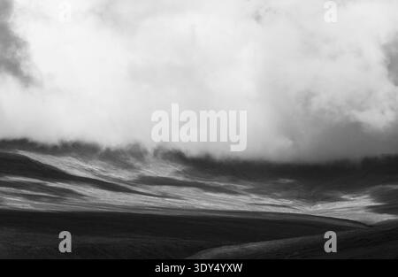 Heavy clouds descending over the moorland slopes of Nidderdale in black and white Stock Photo