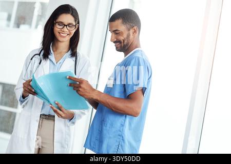 Doctor, nurse and reading file in hospital for patient records, medical report and information. Team, people and document with compliance form Stock Photo
