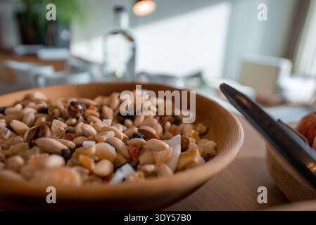 Wooden bowl of mixed nuts and dried fruit on breakfast table Stock Photo