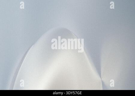 A blurry abstract image showing a light area surrounded by a muted gray and white color gradient effect Stock Photo