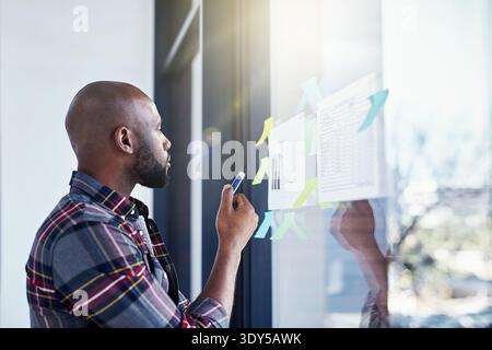 Black man, thinking and document on glass for agenda, strategy and workflow timeline in office. Business person, reading or planning on window for Stock Photo