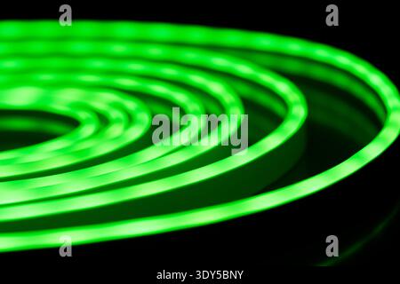 Green glowing LED neon rope light spiral on black background Stock Photo