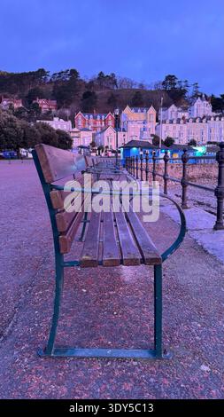 Llandudno North Shore sunrise, view from the promenade, sea view bench in foreground, pier and Grand Hotel in background, tourism, historic Wales Stock Photo