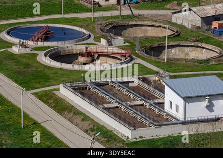 Circular tanks for wastewater processing and filtration are visible at this facility located in a rural setting, surrounded by green grass and pathway Stock Photo
