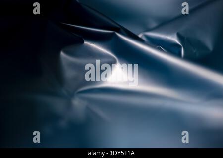 Folded dark blue plastic creating an elegant and mysterious abstract pattern. Folds ripple with texture and subtle depth. Cool tones evoke mystery and Stock Photo