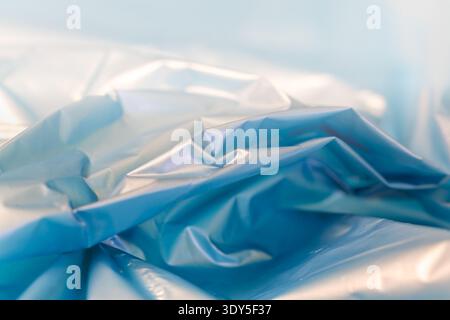 Smooth blue plastic drapes softly with gentle folds. Light catches its surface, creating a subtle sheen. Soft background enhances the serene, cool ton Stock Photo