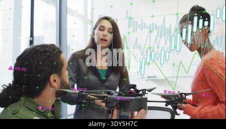 Presenting three team members discussing drone in meeting room, gray blazer gesturing, charts Stock Photo