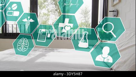Floating teal hexagonal medical icons hovering over bed with sheet near black-framed window in room Stock Photo