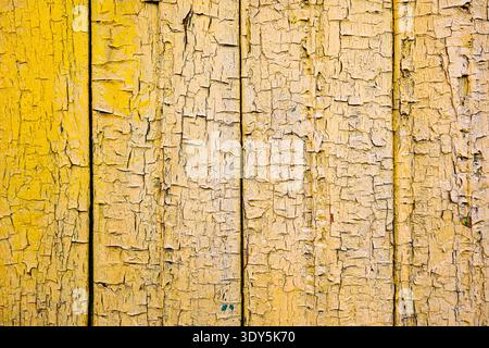 Old yellow cracked paint on wooden planks creating a beautiful textured background Stock Photo