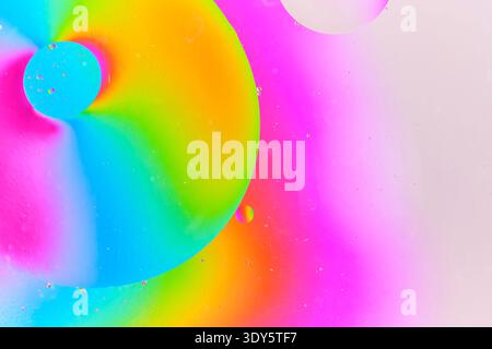 Abstract macro photography of vibrant magenta and green liquid spheres floating in colorful medium Stock Photo
