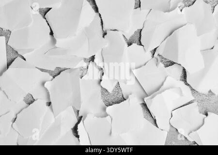 High contrast composition torn white paper pieces layered over dark textured surface Stock Photo