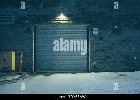 Garage door at night surround by snow and falling snow flakes Stock Photo