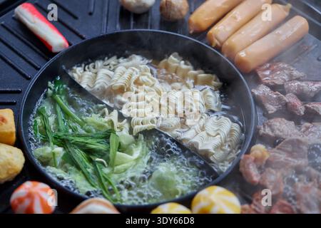 Asian Hot Pot and Grill Meal with Noodles and Meat Stock Photo