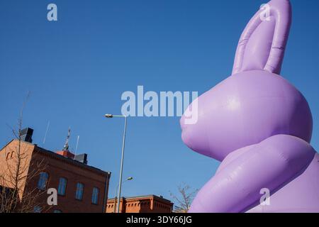 Giant inflatable purple Easter bunny statue standing in city center. Traditional Easter celebration city decoration Stock Photo