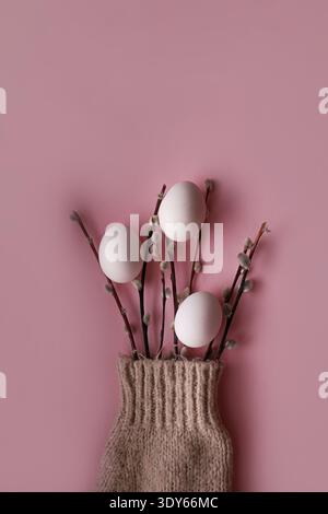Delicate willow branches and eggs arranged on soft pink surface Stock Photo