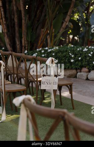 Row Reserved Sign on a Wooden Chair at Outdoor Wedding Ceremony Stock Photo