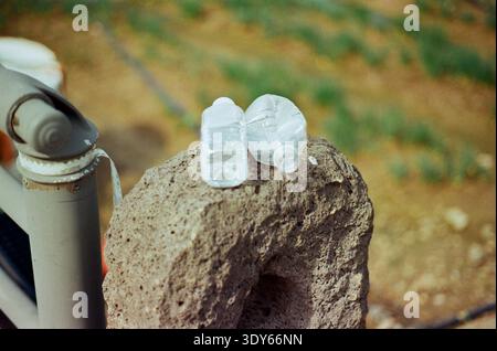 Close-up of two clear plastic bottles resting on a rough porous stone in an outdoor natural setting with soft blurred background. Stock Photo