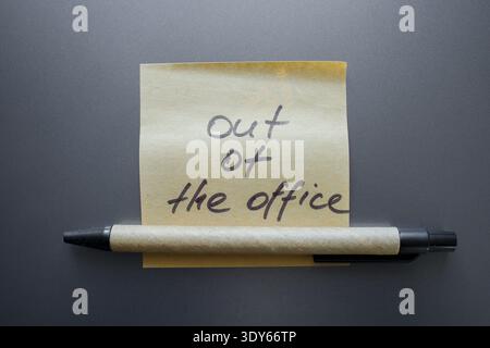 Sticky note with handwritten phrase out of office on a laptop with marker close up. Temporarily unavailable concept, vacation, business trip or person Stock Photo