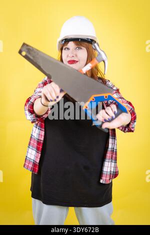 Woman worker presenting saw and hammer for building project Stock Photo