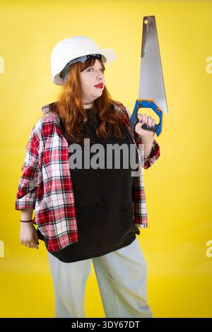 Confident young woman holding saw ready for building Stock Photo