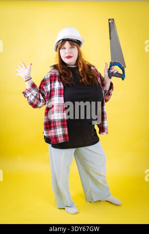 Woman wearing hard hat holding saw ready for work Stock Photo