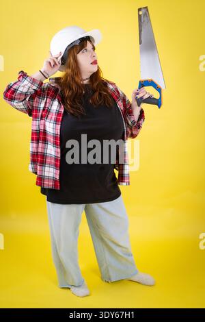 Woman worker thinking while holding hand saw Stock Photo