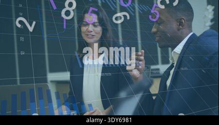 Discussing two professionals reviewing data at office, wearing suits with laptop, data overlays Stock Photo
