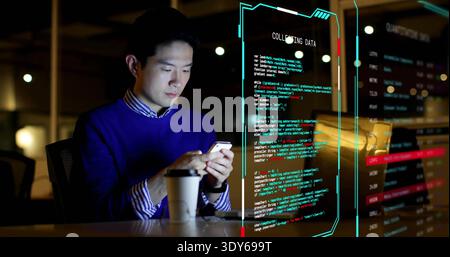 Working man in blue sweater checking phone at office with laptop, coffee, code overlay, copy space Stock Photo