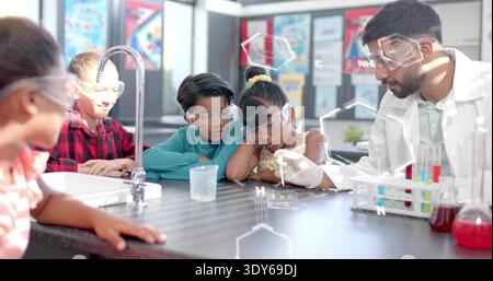 Guiding instructor in lab coat and goggles demonstrating pipette in school lab, with test tubes Stock Photo