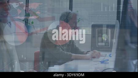Working man wearing green sweater and headset analyzing dashboard on monitor with blinds and plants Stock Photo
