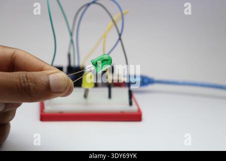 Light emitting diodes or called as LED commonly finds its application in electronics held in hand with breadboard and cables on the background Stock Photo