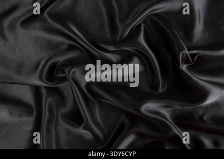 Black silk satin fabric with subtle folds and abstract waves for a luxurious background Stock Photo