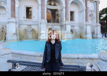 Stylish red-haired woman near a famous fountain and landmark. Travel and tourism concept. Stock Photo
