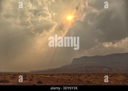 Sun shines through smoke from Dragon Bravo Wildfire over Vermilion Cliffs in Arizona Stock Photo
