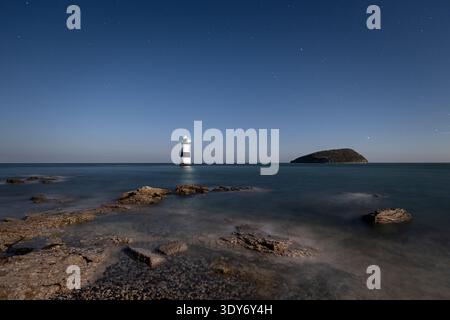 Night sky shines over Trwyn Du lighthouse at Penmon Point on the Isle of Anglesey in North Wales Stock Photo