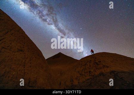 Man looks up at the Milky Way in the desert at night in Argentina with mountains in the background Stock Photo