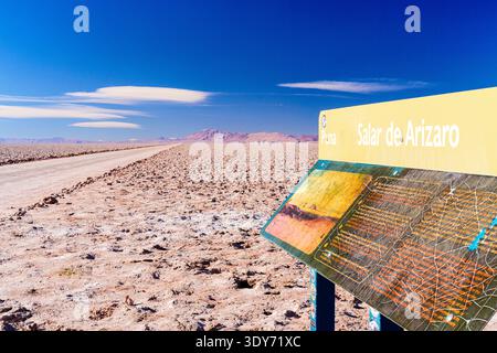 Sign board on side of empty road in Salar de Arizaro salt flat in Puna, Argentina under blue sky Stock Photo