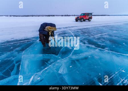 Canadian photographer captures scene on frozen great lake with vehicle nearby in winter light Stock Photo
