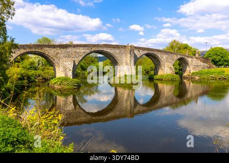 Old Stirling Bridge spans River Forth with reflections and greenery in the city of Stirling in Scotland reflecting on clear waters Stock Photo