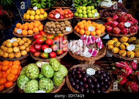 Fresh fruits in baskets at a vibrant tropical fruit market in Portugal during a busy day Stock Photo