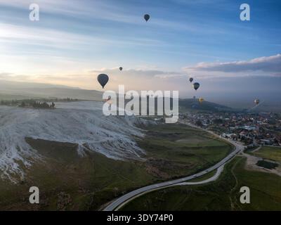 Hot air balloons rise above Pamukkale at sunrise in Turkey with a view of the landscape below Stock Photo