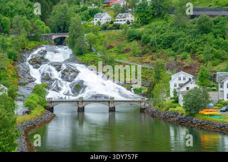 View of Hellesylt waterfall flowing down rocks near houses and bridge in Hellesylt, Stranda Municipality, Norway Stock Photo