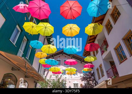 Colorful umbrellas brighten the streets on a sunny day in Zell am See, Salzburg, Austria Stock Photo